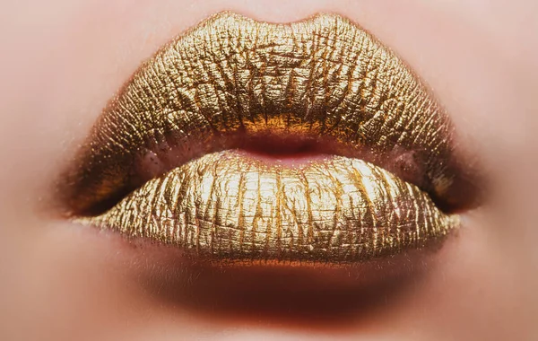 Goldene Lippen. Frau hautnah mit goldenem Lippenstift auf der Lippe. Glitzernde Lippen beißen. — Stockfoto