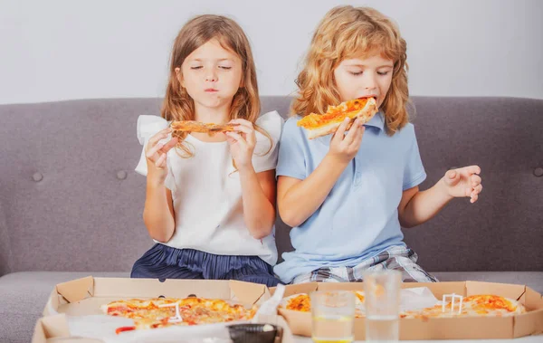 Niña y niño comen pizza. Niños hambrientos comiendo pizza. Comida rápida poco saludable. — Foto de Stock
