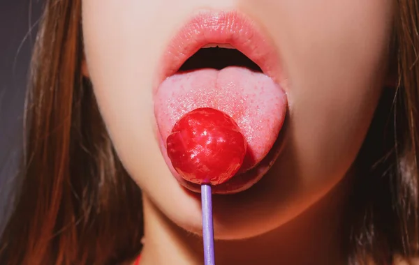Chica con la boca sexy comiendo chupa chups de cerca. Labios de mujer chupando palomitas. Mujer sosteniendo piruleta en la boca, de cerca. Labios rojos, concepto sensual y sexy. — Foto de Stock