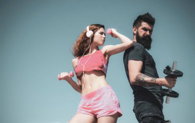 Güzel, zayıf, seksi, güzel vücutlu seksi bir kadın seksi spor kıyafetleri giyiyor ve yakışıklı sakallı koçuyla spor egzersizleri yapıyor. Etkin yaşam tarzı kavramı.