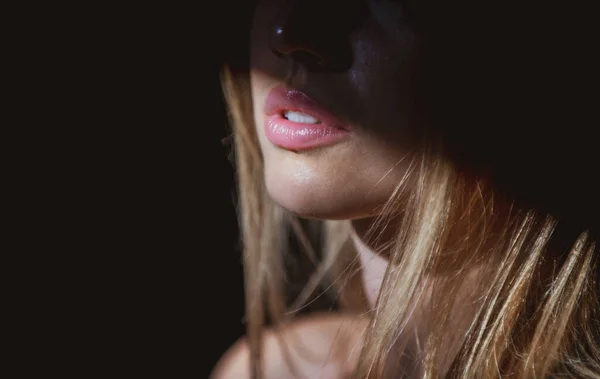 Mujer joven posando en el estudio sobre fondo negro. Luz y sombra en los labios. Retrato de moda de mujer hermosa con luz oscura en la cara. — Foto de Stock