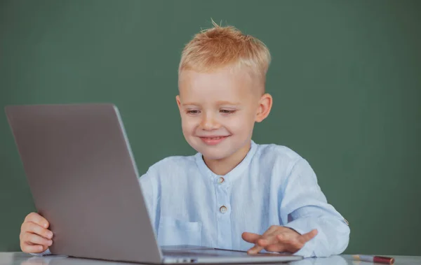Criança sorrindo bonito usando computador portátil, menino estudando através de e-learning online. Pequeno programador engraçado. — Fotografia de Stock