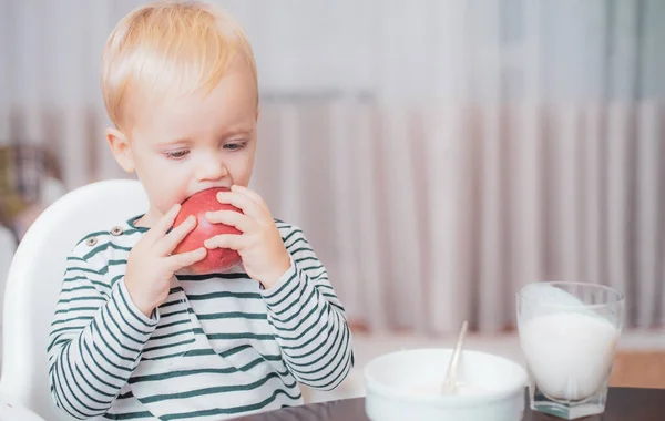 Toddler evde atıştırmalık yiyor. Çocuk lapa yer. Çocuk sevimli çocuk mavi gözleri tabak ve gıda ile masada oturup. Sağlıklı beslenme. Sağlıklı yiyecekler. Çocuk sevimli bebek kahvaltı yiyor. Bebek beslenmesi. Sağlıklı yiyin — Stok fotoğraf