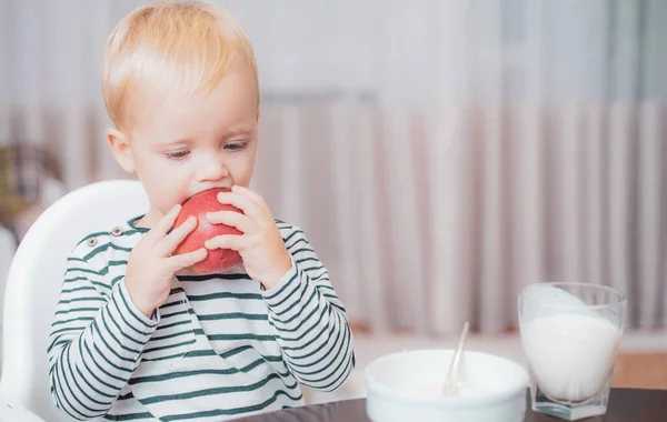 Un niño comiendo algo en casa. Los niños comen gachas. Niño lindo niño ojos azules sentarse en la mesa con plato y comida. Nutrición saludable. Comida saludable. Niño lindo bebé desayunando. Nutrición del bebé. Comer sano — Foto de Stock