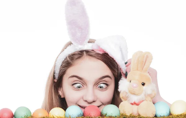 Chica sorprendida usar orejas de conejo en el día de Pascua. Mujer joven con huevos pintados en hierba verde, primavera. Feliz concepto de Pascua. Linda chica con huevos de Pascua decorados aislados en el fondo blanco . — Foto de Stock