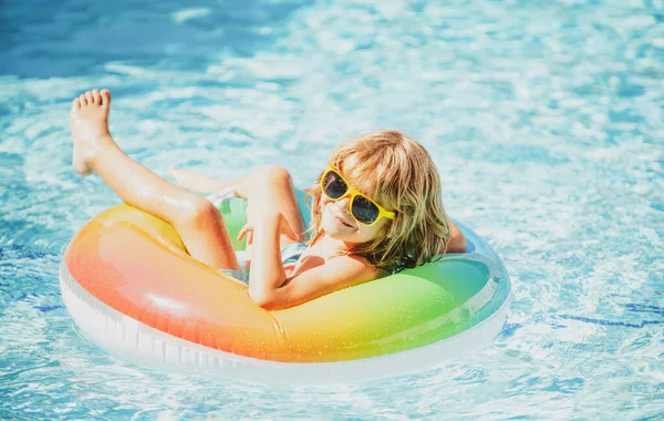 Vacances aquapark pour enfants. Week-end d'été. Garçon drôle dans la piscine sur le cercle en caoutchouc gonflable. — Photo