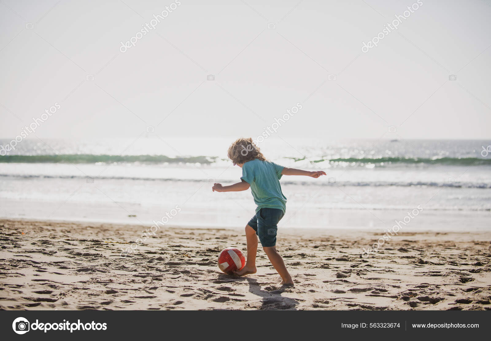 Милый Мальчик Играет В Футбол С Мячом На Песчаном Пляже. Летний.