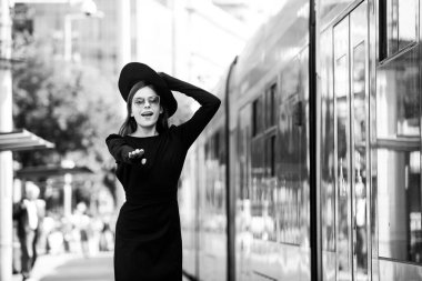 Şehir caddesinde tramvay otobüsünün peşinden koşan güzel genç bir kadın. Güzel, genç bir moda kadını. Şehirde seyahat etmek..