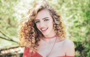 Mükemmel kıvırcık saçlı. Sarışın kıvırcık uzun saçlı. Bahar güneşli arka plan üzerinde gülümseyen mükemmel kadın. Güzellik ve sağlıklı saç. Güzellik modeli mükemmel temiz deri ile. İyi saç.