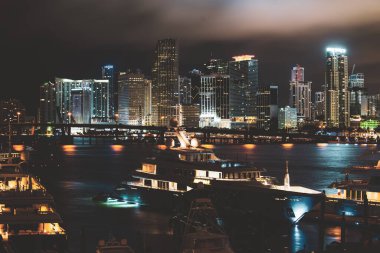 Florida Limanı. Günbatımında Miami Florida, aydınlık binaların ufuk çizgisi ve Macarthur Köprüsü.