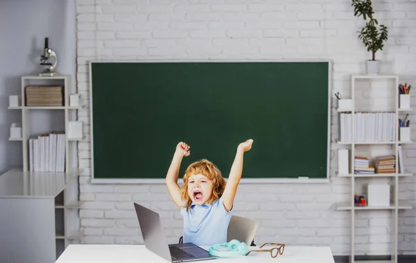 Opgewonden schoolkind leerling met laptop computer in de klas op school. — Stockfoto