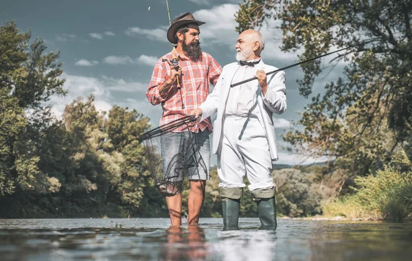 Concepto de familia feliz - padre e hijo juntos. Volar pescador en el río. Pesca en el río. Hombre pescando. Generaciones de hombres. La pesca se convirtió en una actividad recreativa popular . —  Fotos de Stock