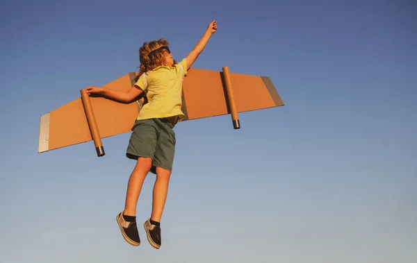 Líder de niños y ganador, arranque de éxito. Un piloto vuela contra un cielo azul. Emocionado niño jugar con juguete jetpack alas superhéroe en el parque. — Foto de Stock