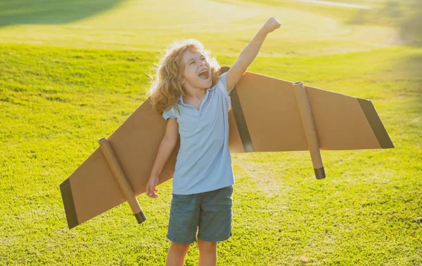 Menino brincando e sonhando com férias de verão e viagens. Crianças imaginação e liberdade conceito. Criança se divertindo com asas de papel de brinquedo. — Fotografia de Stock