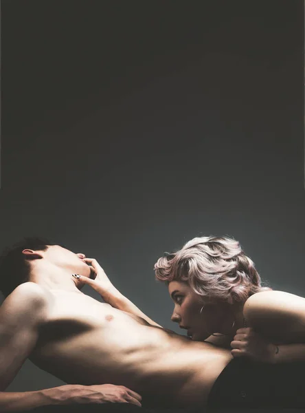 A szexi pár a szerelmi játékokban játszik. Egy nő szexi fehérneműben fekszik egy férfin. Szoros kép a meztelen érzéki pár fiatal szőke hölgy ölelése és csók férfi gyönyörű izmos test. — Stock Fotó