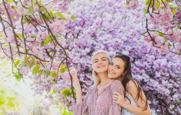 Två unga kvinnor som kopplar av i Sakura blommor. Vårflickor. — Stockfoto