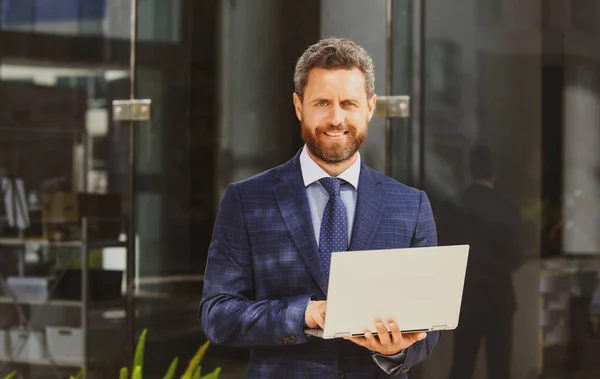 Retrato de hombre de negocios guapo usando el ordenador portátil al aire libre. —  Fotos de Stock