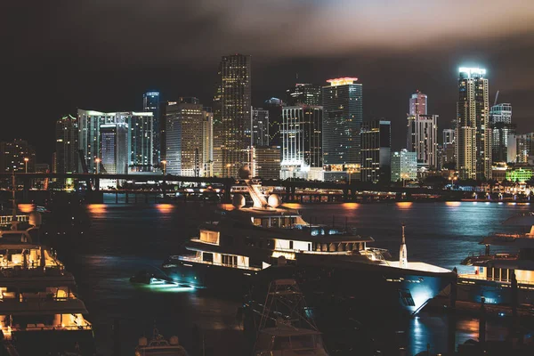 Florida Limanı. Günbatımında Miami Florida, aydınlık binaların ufuk çizgisi ve Macarthur Köprüsü.