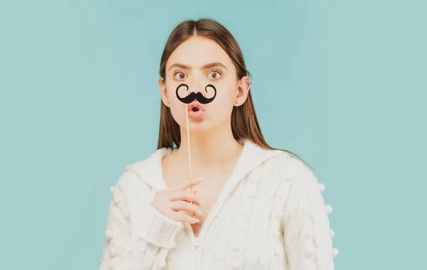 Crazy emotions. Just having fun. Woman holding fake mustache on her face. Suprised girl with moustache on stick.