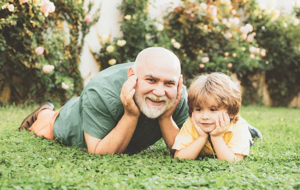 Baba oğul ve büyükbaba birlikte dinleniyorlar. Sevgi dolu bir aile. Babalar Günü. İki kuşak - birlikte hafta sonu. Emekli ebeveyn. Torunuyla parkta koşan son sınıf öğrencisi..