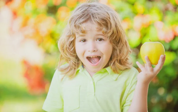 Gelukkige kleine jongen die groene appel eet. Glimlachend kind houdt en eet verse appel, tuin achtergrond. Portret van schattig gelukkig kind bijt appel. — Stockfoto