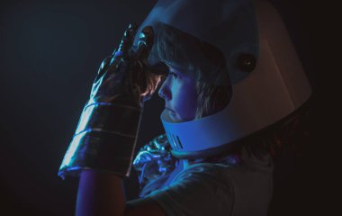 Kapalı çocuk portresi siyah, macera hayalinde izole edilmiş. Küçük astronotun yakından çekilmiş yüzü ve kaskı rüya gibi görünüyor. Kopya alanı ile izole edilmiş arkaplan.