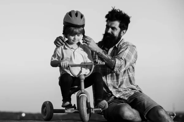 Help kid explore world. Happy loving family Father and son. Little boy wearing helmet while learning to ride cycle with his daddy.