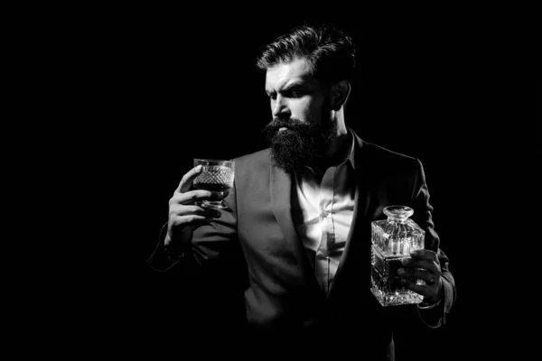 Whisky elegáns. A szakállas férfi egy pohár brandyt tart a kezében. Szakállas üzletember elegáns öltönyben, egy pohár whiskyvel. Luxusital-koncepció. — Stock Fotó