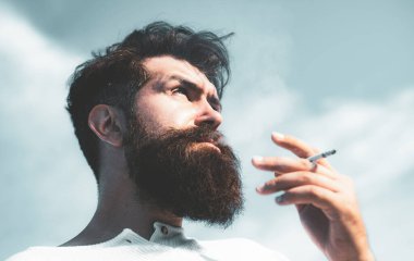 Yakışıklı genç adam dışarıda sigara içiyor, başka tarafa bakıyor..