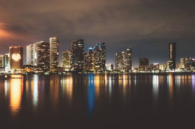 Miami silueti. Miami Florida, gün batımı manzarası. Biscayne Körfezi 'nde renkli iş yerleri, konut binaları ve köprü..