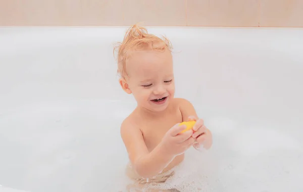 浴室里微笑的孩子有趣的婴儿玩水和泡沫在一个大厨房水槽。有趣的欢快的幼儿清洁身体在浴缸. — 图库照片