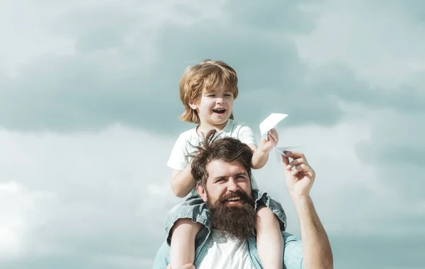 Padre e figlio giocano insieme. Padre e figlio costruiscono insieme un aeroplano di carta. Padre e figlio godono all'aperto. Godere . — Foto Stock