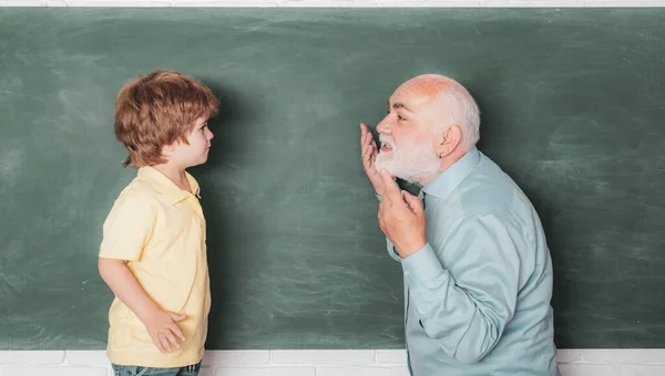 Docent en school jongen met computer in de klas over Blackboard. Portret van grootvader en kleinzoon tijdens het werken in school klasse over Green Blackboard. Vader en zoon. — Stockfoto