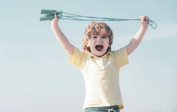 青空の背景にジャンプロープで運動するかわいい少年の肖像画。晴れた朝の間にロープをスキップする子供. — ストック写真
