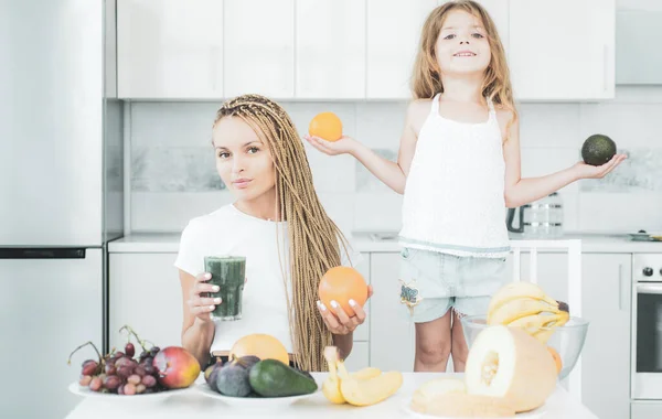 Sağlıklı çocuk büyümesi. Anne ve kızı meyvelerle kokteyli karıştırıyor. Anne ve kızı mutfakta yeşil smoothie içiyorlar. Mutlu aile. — Stok fotoğraf