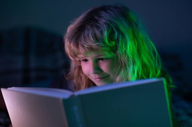 Kitap okuyan şirin bir çocuk. Açık kitabı olan bir çocuk. Ev okulu dersi. Evde kitap okumaya odaklanmış küçük bir çocuk. Hayal gücü ya da öğrenme kavramı.