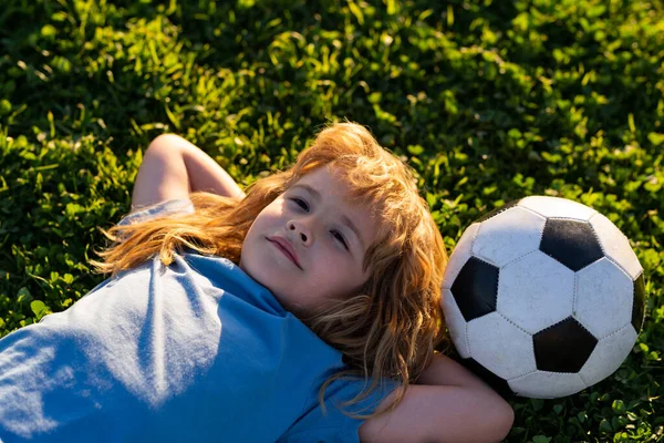 Piłkarz marzący, leżący na trawie. Słodkie małe dziecko marzy o zostaniu piłkarzem. — Zdjęcie stockowe