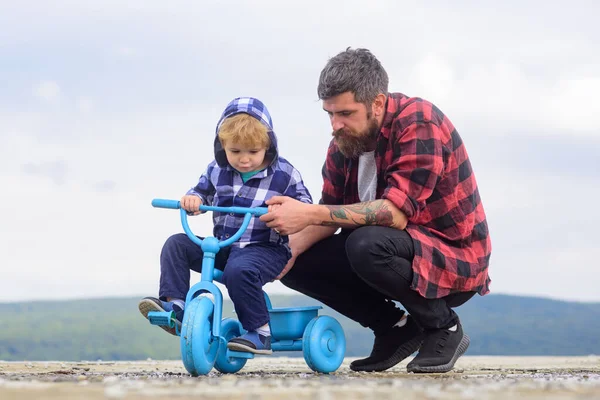 Little boy learn to ride a bike with his daddy. Dad teaching son to ride bicycle. Father teaching his son cycling. Fathers day.