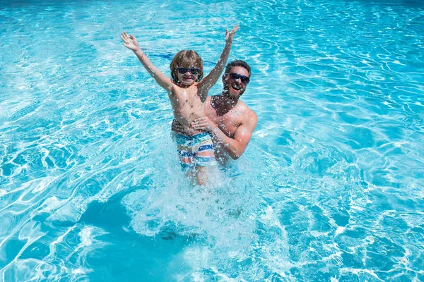 Roztomilé nadšené dítě s tátou v letním bazénu. Šťastný chlapec natahuje ruce, zatímco jeho otec ho nese v bazénu. — Stock fotografie