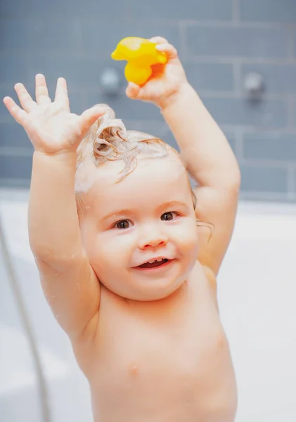 Lächelndes Kind im Badezimmer mit Spielzeugente. Glückliches lustiges Baby in der Badewanne gebadet. — Stockfoto