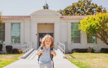Mutlu gülümseyen çocuk okula gidiyor. Çantalı çocuk ilkokula gidiyor. İlkokul. Öğrenci git sırt çantasıyla çalış..