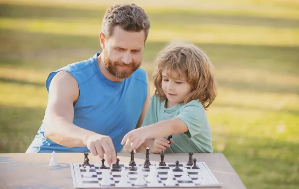 Padre e figlio giocano a scacchi insieme all'aperto. Il ragazzo gioca a scacchi. — Foto Stock