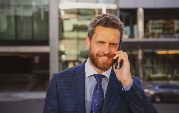 Liikemies puhuu puhelimessa. Muotokuva iloinen liikemies toimistotyöntekijä puhuu matkapuhelimella seisoessaan lähellä modernia toimistoa. — kuvapankkivalokuva