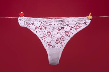 Tanga bikini iç çamaşırı, beyaz dantelli iç çamaşırı kırmızı arka planda izole edilmiş halat..