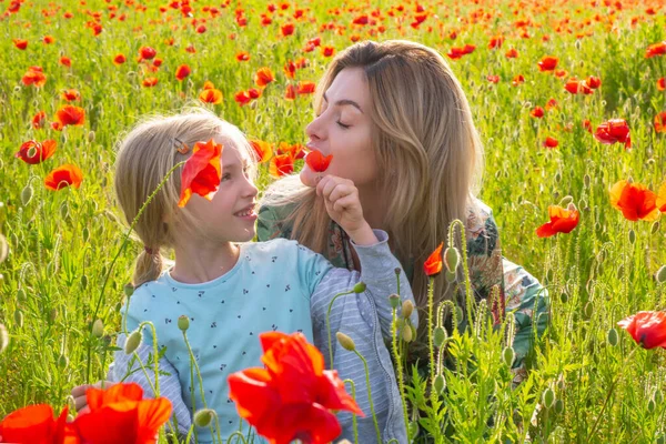 Μητέρα με κόρη στο χωράφι με τις παπαρούνες. Η μαμά αγκαλιάζει ένα υπέροχο παιδί σε φόντο παπαρούνας. Η οικογένεια στο λιβάδι με τα άνθη της άνοιξης. — Φωτογραφία Αρχείου