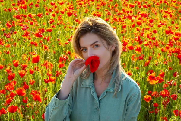 Женщина на маковом лугу. Красивая девушка на маковом поле под открытым небом. Маки цветы у рта. — стоковое фото