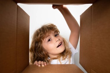 Çocuk kutuları açıyor, kutuları açıyor ve sürpriz bir yüz ifadesiyle içeri bakıyor. Çocuklar için karton kutu açıyorum..