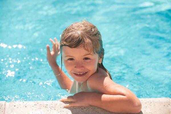Barnpojken simmar i poolen. Glad liten pojke leker med i utomhuspoolen på varm sommardag. Barn lär sig simma. Familjesemester. — Stockfoto