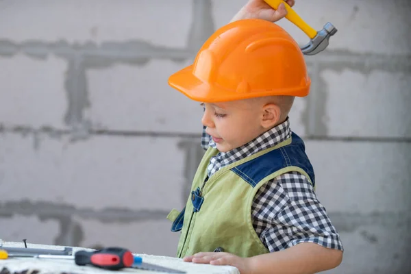 Portret van kleine bouwer in hardhoeden met instrumenten voor renovatie op de bouw. Bouwjongen, timmerman jongen met bouwgereedschap set. Kinderen bouwer en reparatie. — Stockfoto