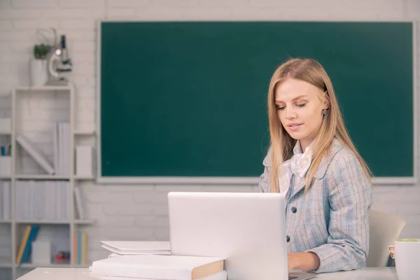 Vrouwelijke student zit aan tafel en schrijft op schrift in de klas op de middelbare school of hogeschool. — Stockfoto